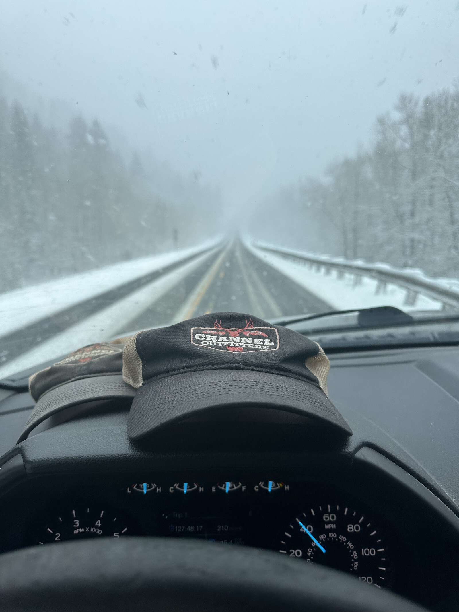Channel Outfitters hat on the dashboard, snowy Swan Highway through the windshield